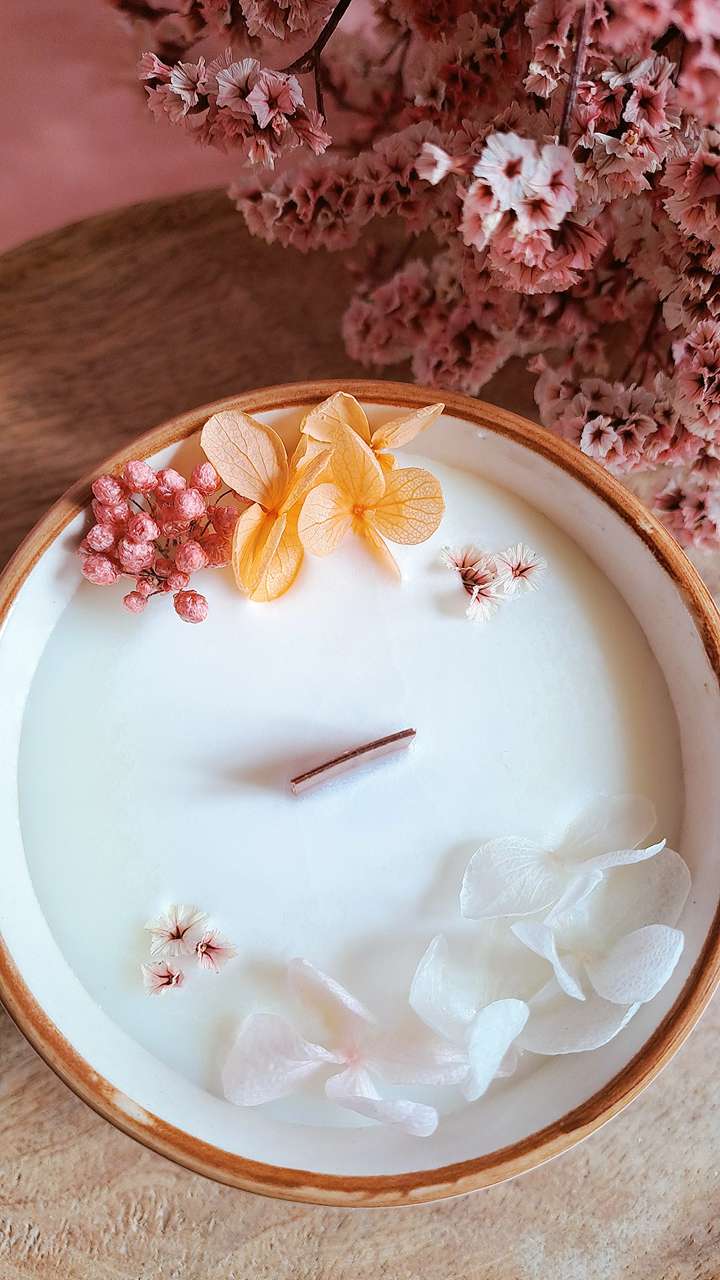 Bougie artisanale décorée avec fleurs séchées.